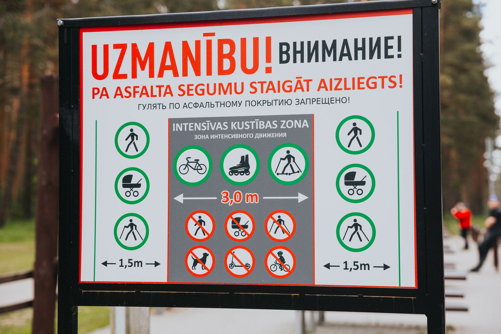 Informācijas plāksne pie trases ar satiksmes noteikumiem latviešu un krievu valodā: zonas gājējiem, ratiņiem, nūjotājiem, velosipēdistiem, skrituļotājiem un skrituļslēpotājiem.