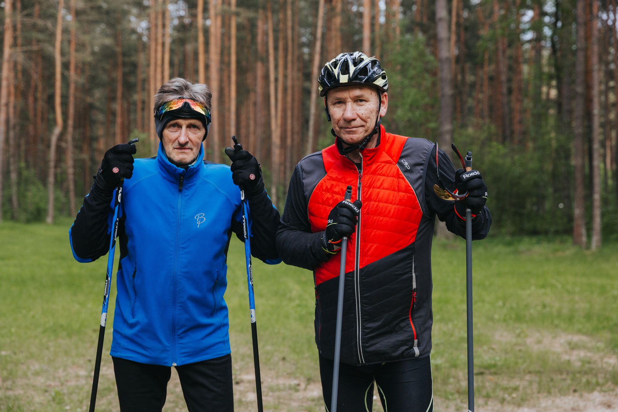 Pjotrs stāv blakus citam sportistam meža fonā; abi ekipējumā, ar nūjām.