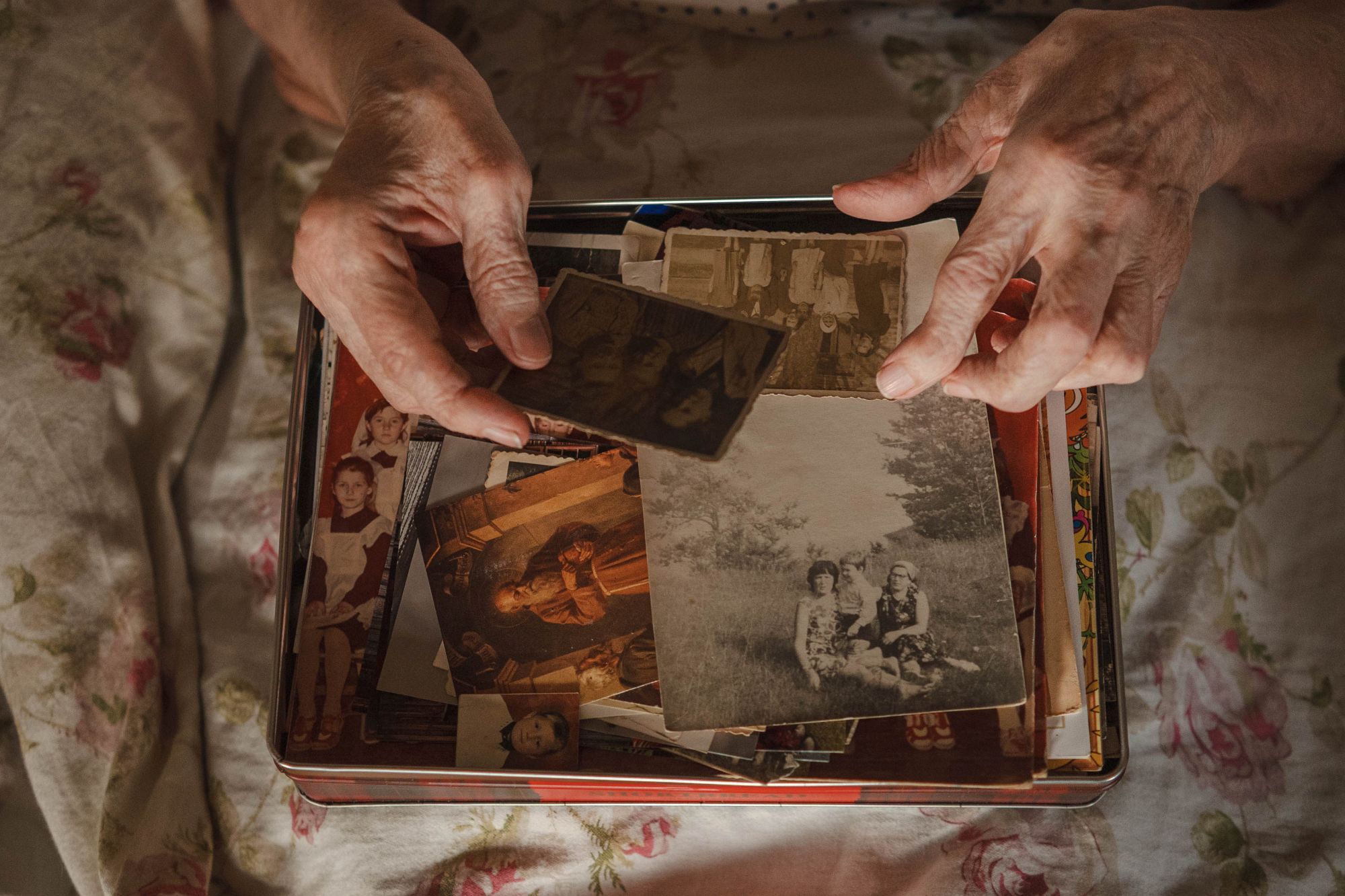 Veronikas rokas šķirsta kasti ar vecām fotogrāfijām.