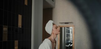 Woman in white robe standing in front of mirror. Photo: Henry Ravenscroft