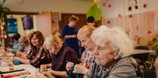 Senioru nodarbība paklāju pīšanā no otrreizējiem materiāliem Dienas aprūpes centrā Višķos. Priekšplānā – Lūcija (90 gadi). 2026. gada 17. marts. Foto: Irina Maskaļenko